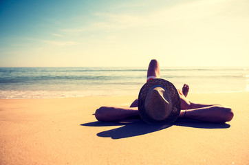 Unrecognizable man in vintage beach hat relaxing on the smooth sand of an empty beach