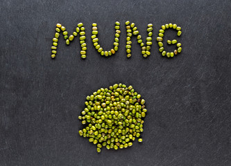 Dried green mung beans on dark stone background. Flat lay.
