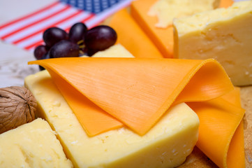 Cheese collection, blocks and slices of yellow and matured american cheddar cheese with flag of USA