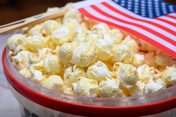 Plastic bucket with sweet popcorn ready to eat and flag of USA