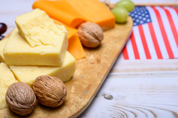 Cheese collection, blocks and slices of yellow and matured american cheddar cheese and Californian walnuts with flag of USA
