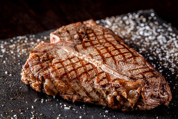 American cuisine. Juicy grilled T-Bone steak grilled with spices and salt. Close-up. background...
