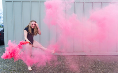 Teenage ballet dancer with colorful red smoke bomb