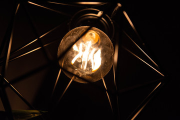 Closeup of vintage style light bulb in decorative lamp shade. 