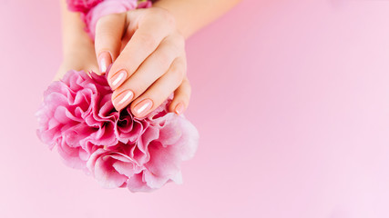Beautiful Woman Hands with fresh eustoma. Spa and Manicure concept. Female hands with pink manicure. Soft skin, skincare concept. Beauty nails. Over beige background