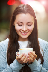 Close up of a woman hands holding a hot coffee cup outside with outdoors in the background