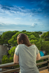 Fototapeta na wymiar Wonderer woman wearing sport clothes and standing on amazing view jotel balcony looking to ocean.