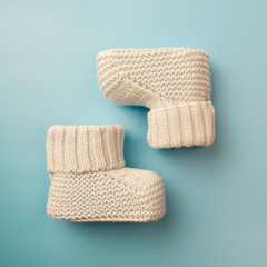 Baby booties. Knitted socks on blue background, footwear for newborns.