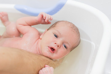 Fototapeta na wymiar Little newborn baby having a bath. Hardening, hygiene of the newborn.