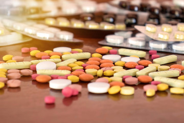 Many tablets of various colors on a wooden floor. The concept of drug use.