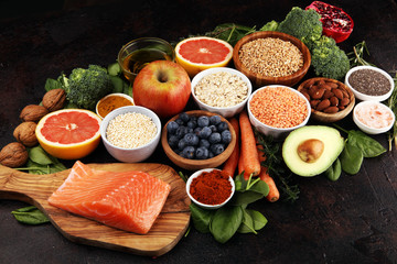 Healthy food clean eating selection: fish, fruit, vegetable, cereal, leaf vegetable on rustic background