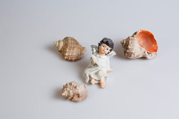 Obraz na płótnie Canvas figurine of a little girl and shells on a white background