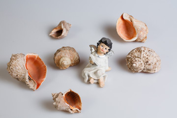 figurine of a little girl and shells on a white background