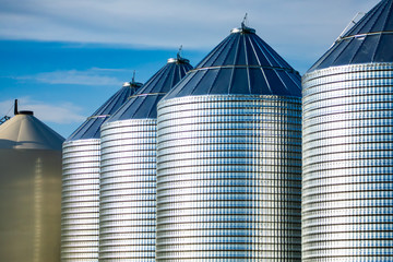 Large steel cylinder towers are seen on a grain and cereal farm in Saskatchewan, Canada. Silos used to stockpile food grains in an agrarian facility