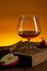 glass of Calvados Brandy and red apples on wooden