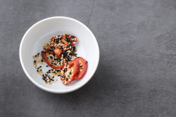 white plate with chopped pepper and sesame seeds on a gray background