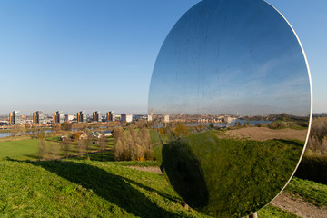 skyline of Carnisselande Barendrecht taken from â€œGaatkensbultâ€ and also seen in the reflection of the big round mirror on top. Taken on a sunny day in the morning with a blue sky.