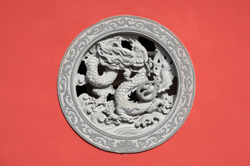 Stone dragon relief - window made of decorated stone relief, ornaments and relief on the red wall from Chinese buddhism temple, Fujian,China.