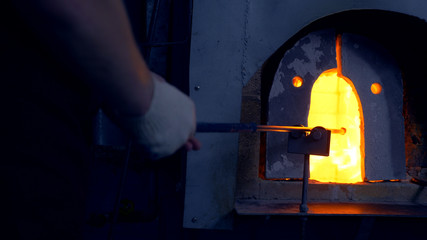 glassblower. manufacturer of glass products. man heats glass in a furnace