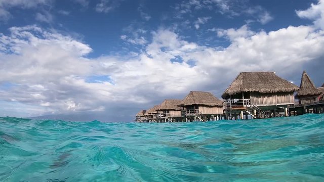 Overwater bungalow villas, kayaking in turquoise lagoon. Moorea, Tahiti French Polynesia. Luxury travel vacation & paradise getaway, romantic honeymoon exotic destination.  