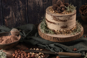 Delicious naked chocolate and hazelnuts cake on table rustic wood kitchen countertop.