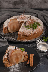 Delicious spice cake with pear, ginger and cinnamon on a dark kitchen counter.
