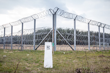 Border fence between Subotica (Serbia) & Kelebia (Hungary) with a boundary marker. This border wall...
