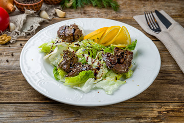 Salad with chicken liver on white plate