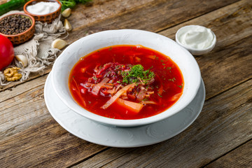 Borscht with sour cream on wooden table