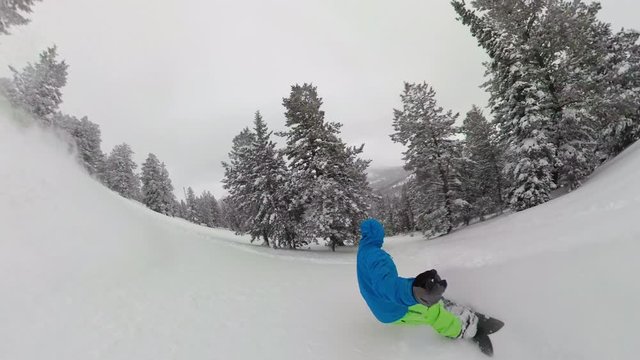 SELFIE: Breathtaking shot of an extreme male snowboarder speeding down the ungroomed slope in the Rocky Mountains. Male tourist shreds fresh powder snow while cat boarding in the mountains of Wyoming.
