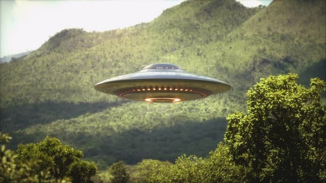 Animation of a flying saucer UFO hovering over forested hills