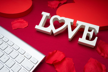Internet dating romance concept. Online Valentine's. Heart shaped paper cutout, keyboard on red background.