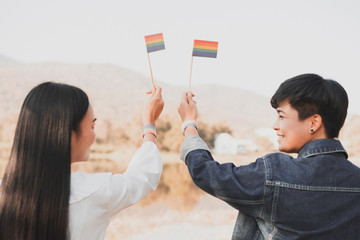 Young women lesbian couple holding a LGBT pride flag . LGBT equal rights concept.