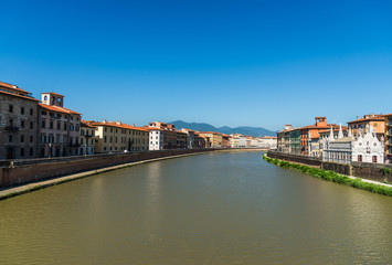 Traditional colorful ancient Italian architecture houses in Pisa, Italy, alongside the embankment of Arno river