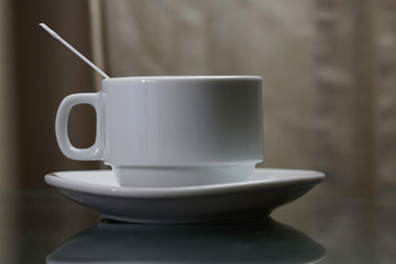 A white coffee cup with  plastic spoon over black background.