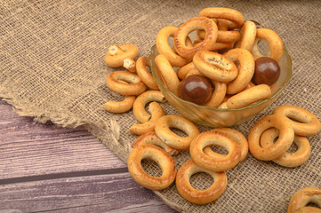 Small bagels, brown sugar and ceramic dishes on a wooden background close-up.