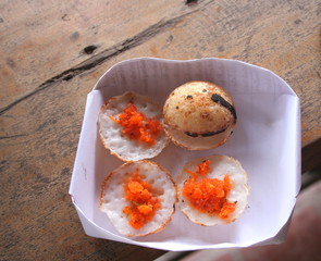 Kanom Krok (Coconut-rice pancakes) are in white paper joist on brown wood table, Thailand.