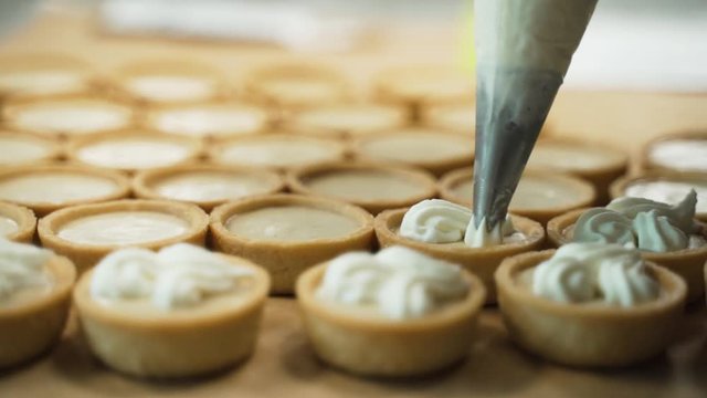 Piping cup cake frosting on mini cup cakes. This was taken at a higher frame rate and has been converted to a slow motion video clip.