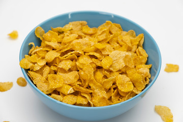 Golden cornflakes in the blue bowl isolated on white background