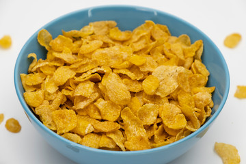 Golden cornflakes in the blue bowl isolated on white background