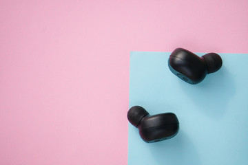 Black true wireless earbuds headphones with power bank case over colorful pastel color.
