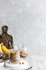 Chocolate banana granola with nuts in a glass jar on a light background