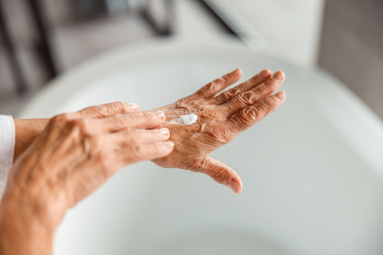 Elderly Lady Applying Moisturizing Cream On Hand