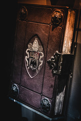 Aged brown leather book with embossed symbols of an eagle, a ship, a book and pope's hat and lock.