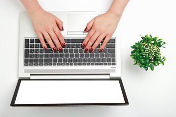 Fototapeta na wymiar Female hands with red manicure are typing on laptop white background top view