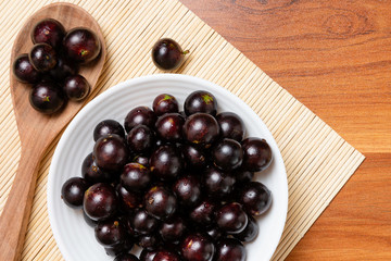 Jabuticaba in the wooden spoon and bowl. Jaboticaba or Jabuticaba is the native Brazilian grape tree. Species Plinia Cauliflora. Brazilian Berry.
