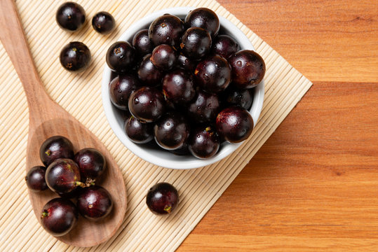 Jabuticaba in the bowl and wooden spoon - top view. Jaboticaba or Jabuticaba is the native Brazilian grape tree. Species Plinia Cauliflora. Brazilian Berry.