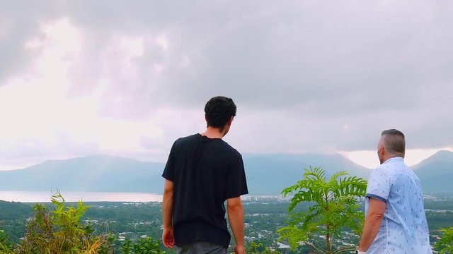 men who stoppted to see the view of the cloud covering the mountains in the distance over a city scape turn and walk out of shot towards camera as they continure on there monring walk in slow motion