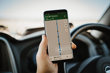 Driver using mobile phone navigation while driving car