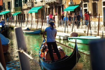 Fototapeta na wymiar Gondolier with tourists guiding his boat through the canals of Venice